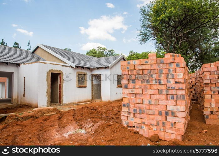 Building material stacked next to the imcomplete house that it is intended for.