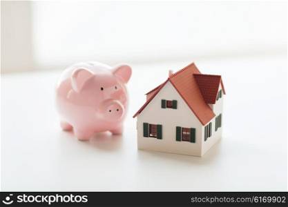 building, mortgage, investment, real estate and property concept - close up of home or house model and piggy bank