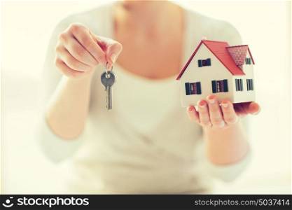 building, mortgage, real estate and property concept - close up of hands holding house model and home keys. close up of hands holding house model and keys