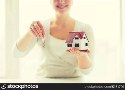 building, mortgage, real estate and property concept - close up of happy woman holding house model and home keys. close up of woman holding house model and keys