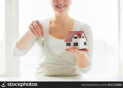 building, mortgage, real estate and property concept - close up of happy woman holding house model and home keys