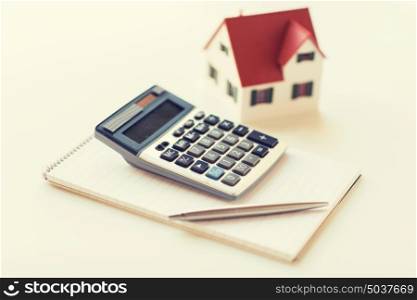 building, mortgage, real estate and property concept - close up of home model, house keys and notebook with pen. close up of home model, calculator and notebook