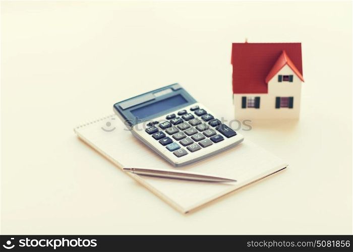 building, mortgage, real estate and property concept - close up of home model, house keys and notebook with pen. close up of home model, calculator and notebook