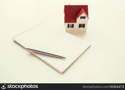 building, mortgage, real estate and property concept - close up of house model, notebook and pencil. close up of house model, notebook and pencil. close up of house model, notebook and pencil