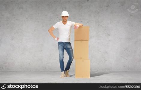 building, moving and postal concept - smiling man in helmet and gloves with tower of cardboard boxes