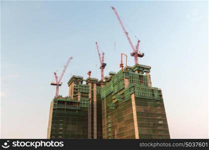 building, real estate and architecture concept - skyscraper and construction cranes. building and construction cranes