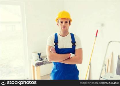 building, repair and people concept - builder in hardhat and overall with working tools indoors