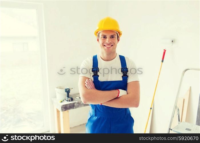 building, repair and people concept - smiling young builder in hardhat with working tools indoors