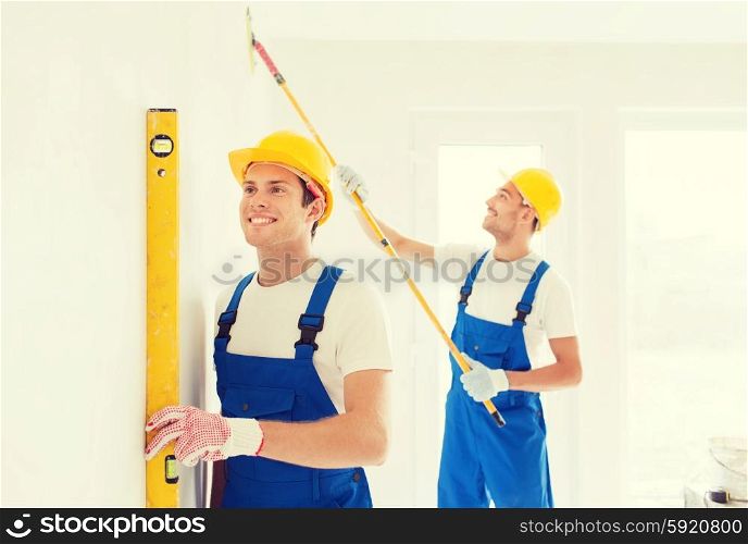 building, teamwork and people concept - group of smiling builders in hardhats with tools indoors