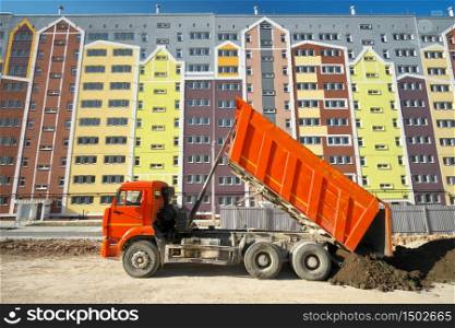 Building urban scene. Multistorey building apartment house and dump truck unload soil at day.
