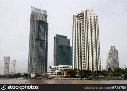 Buildings and ferry boat on the Chao Phraya river in Bangkok, Thailand