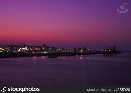 Buildings by the sea lit up at dusk