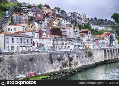 Buildings climb the steep hillsides of the Douro River in the city of Porto in Portugal. A funicular is visible in the upper left as it climbs the hill.