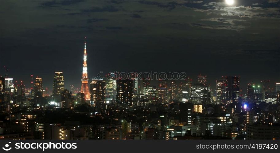 Buildings lit up at night in a city with Tokyo Tower in the background, Tokyo, Japan