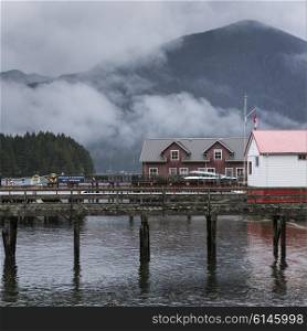 Buildings on a pier with mountains in the background, Pacific Rim National Park Reserve, Tofino, Vancouver Island, British Columbia, Canada