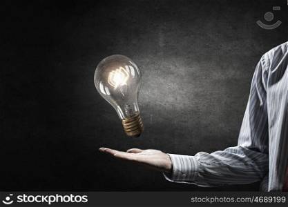 Bulb in hand. Businessman presenting glass glowing light bulb in his hand