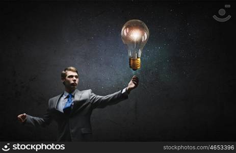 Bulb in hand. Businessman reaching hand to touch glass light bulb