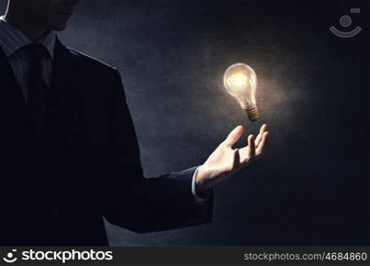 Bulb in hand. Close up of human hand holding glass glowing light bulb