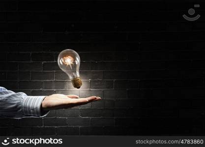 Bulb in hand. Close up of human hand holding glass glowing light bulb