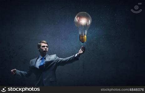 Bulb in hand. Young businessman and glass glowing light bulb