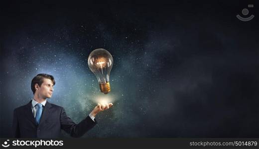 Bulb in hand. Young businessman and glass glowing light bulb