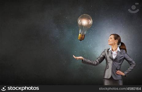 Bulb in hand. Young businesswoman presenting glass glowing light bulb in her hand