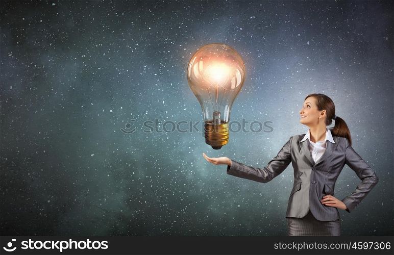 Bulb in hand. Young businesswoman presenting glass glowing light bulb in her hand