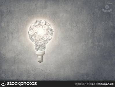 Bulb of gears. Light bulb concept with gears inside on cement background
