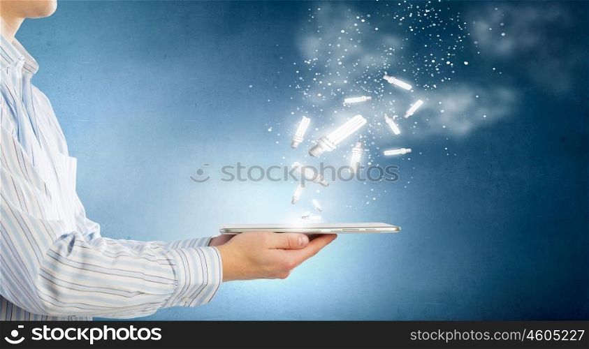 Bulb on tablet. Human hands holding tablet pc with light bulb on it