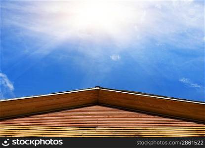 Bulding&acute;s roof and blue sky with a sun behind it