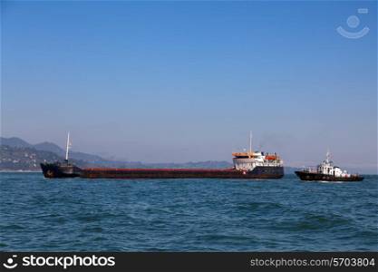Bulk-carrier ship and tugboat moving in the sea&#xA;