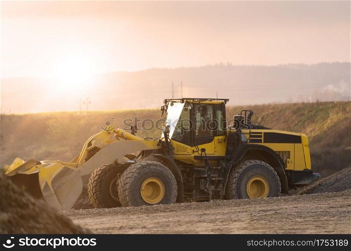 Bulldozer in a gravel pit for earthworks on construction sites. yellow drill without people at sunset. abandoned construction site