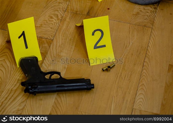 Bullet casings and gun next to markers at crime scene