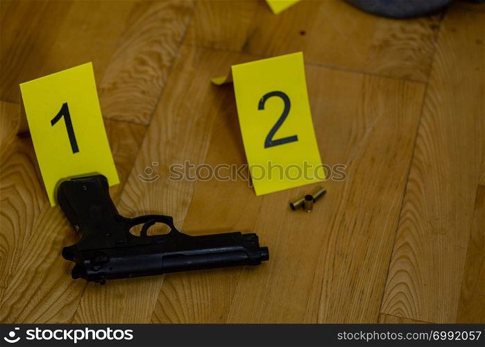 Bullet casings and gun next to markers at crime scene