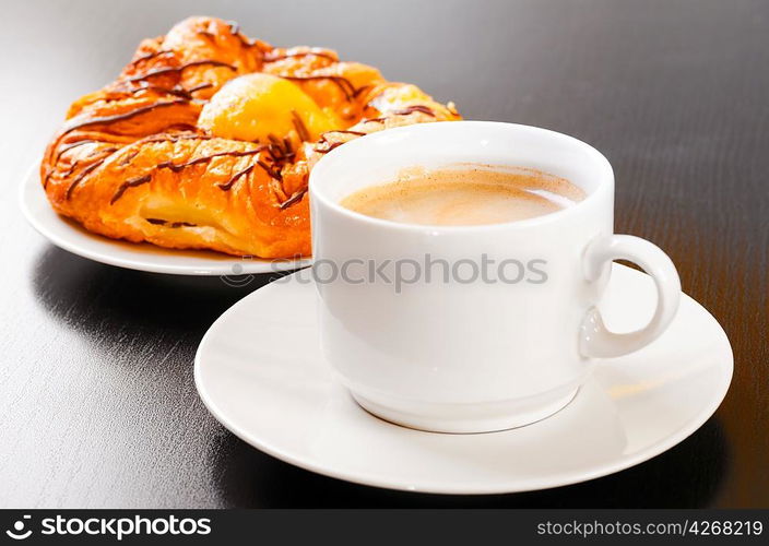 bun and cup of hot evaporating coffee on table