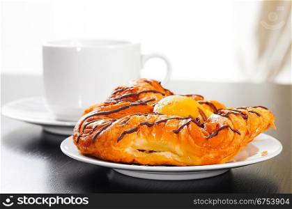 bun and cup of hot evaporating coffee on table