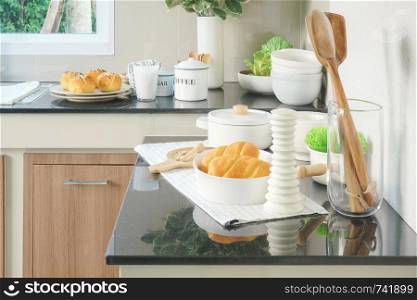 Bun, bread and white ceramic dishware on black counter top in the kitchen
