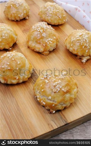 Bun puff pastry with sesame seeds on a wooden board