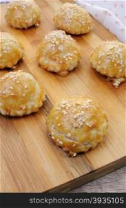 Bun puff pastry with sesame seeds on a wooden board