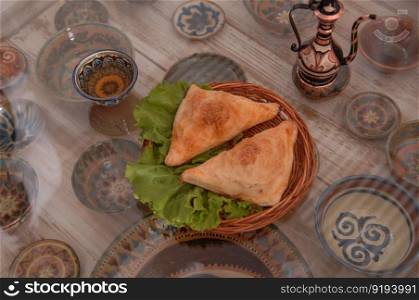 bun with salad in a wicker plate on a surface of glass on the background of the set of cups and pitchers. bun with salad in a wicker plate