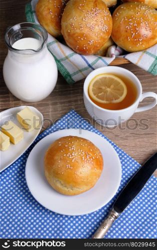 Bun with sesame seeds with slices of butter, milk, tea for breakfast