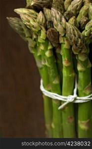 Bunch of asparagus on a wooden table. Shallow depth of field, focusing on the tips.