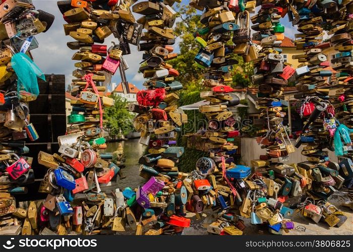 Bunch of colored padlocks left by lovers on the metal railing on the passage near the Charles Bridge over the Vltava river in Prague in the Czech Republic: different shapes and several colours, as red, pink, orange, silver, green, blue, yellow, fuchsia, purple.