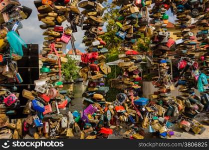 Bunch of colored padlocks left by lovers on the metal railing on the passage near the Charles Bridge over the Vltava river in Prague in the Czech Republic: different shapes and several colours, as red, pink, orange, silver, green, blue, yellow, fuchsia, purple.
