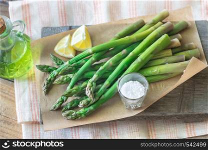 Bunch of cooked asparagus with lemon wedges and sea salt on the wooden board