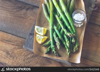 Bunch of cooked asparagus with lemon wedges and sea salt on the wooden board