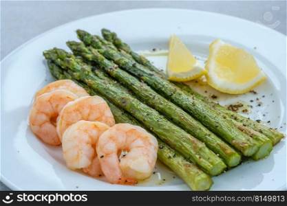 Bunch of cooked asparagus with prawn on the white plate