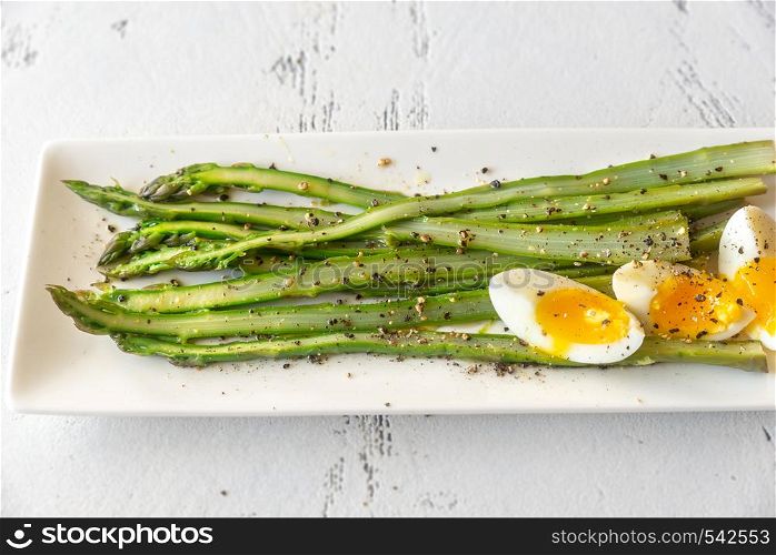 Bunch of cooked asparagus with soft-boiled egg on the white plate