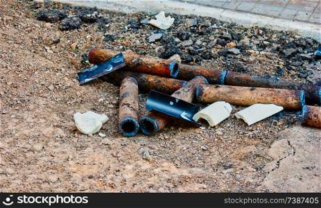 Bunch of corroded rusty pipes lying on ground in the yard. Bunch of rusty pipes lying on ground