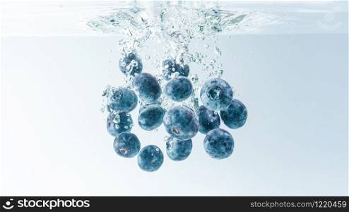 Bunch of delicious looking blueberries splashing into water surface and sinking. Isolated on white background, splash food photography.. Bunch of blueberries splashing into water surface and sinking. Isolated on white background, splash food photography.
